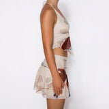 Woman wearing a red and white jacquard mini dress with floral patterns and side cutouts, posing on pink stairs in a summer setting.